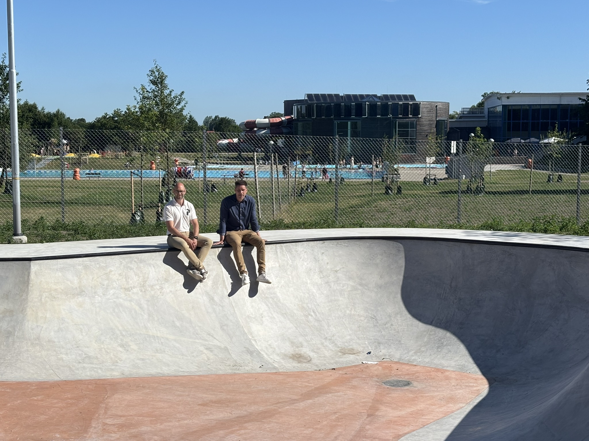 Tv&aring; m&auml;n sitter p&aring; kanten till en skate-bana i betong
