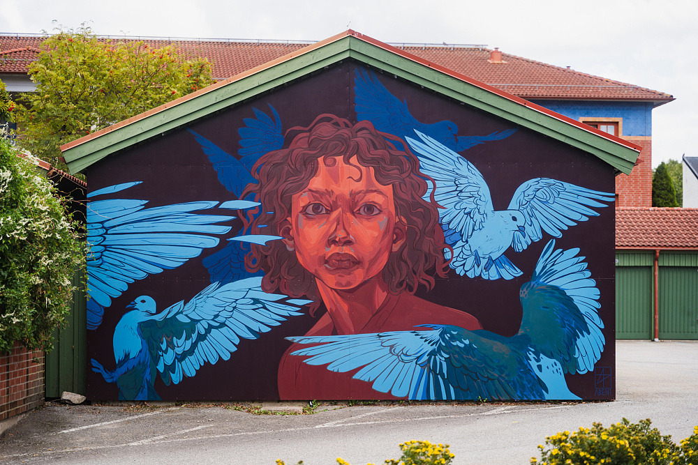 F&auml;rgstark muralm&aring;lning med ett stort portr&auml;tt m&aring;lat &ouml;ver en h&ouml;g husfasad. Konstverket anv&auml;nder starka f&auml;rger och mjuka &ouml;verg&aring;ngar som skapar ett uttrycksfullt och levande motiv.