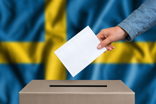 en hand lägger sitt röstkort