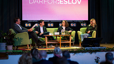 Personer sitter i en soffa på en scen.