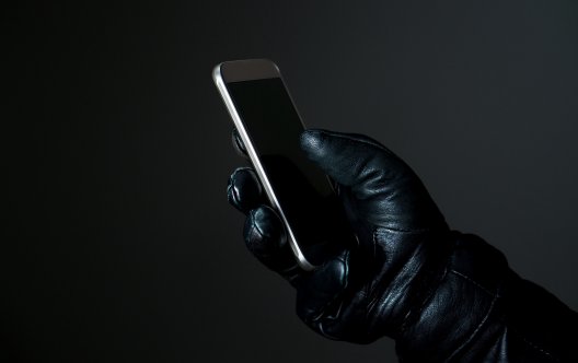 En handskllädd hand med en telefon.