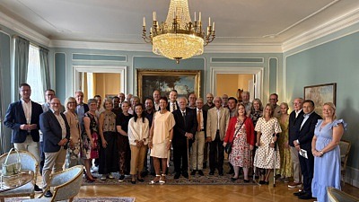 En stor grupp finklädda människor i en festsal med kristallkrona i taket
