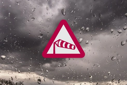 Varningstriangel med symbol för storm mot mörka moln
