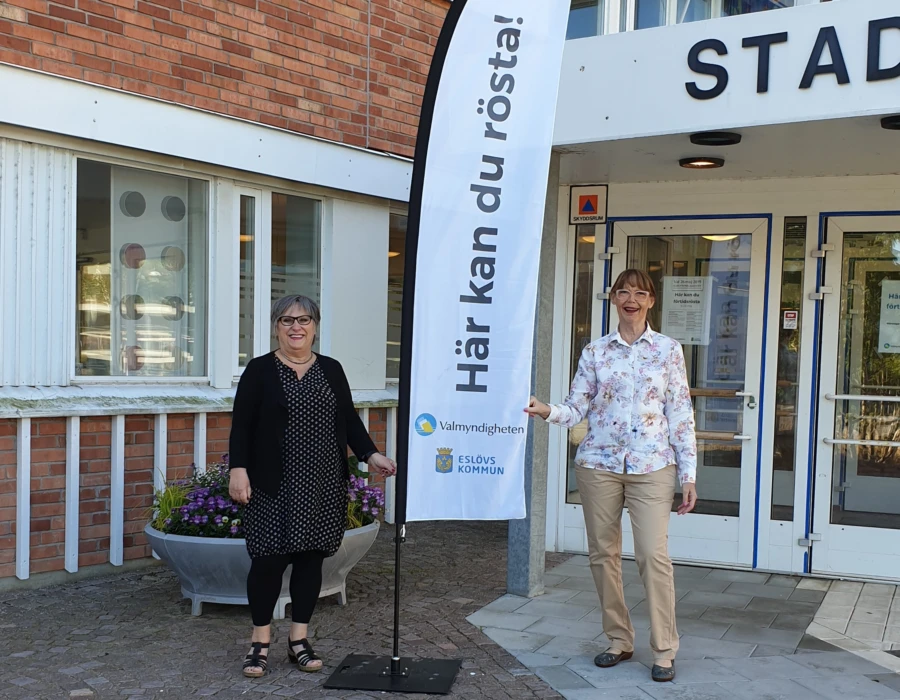 Tv&aring; valarbete framf&ouml;r stadshuset med flagga d&auml;r det st&aring;r H&auml;r kan du r&ouml;sta