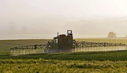 En traktor sprider bekämpningsmedel på en åker.