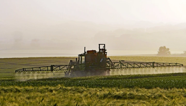 En traktor sprider bekämpningsmedel på en åker.