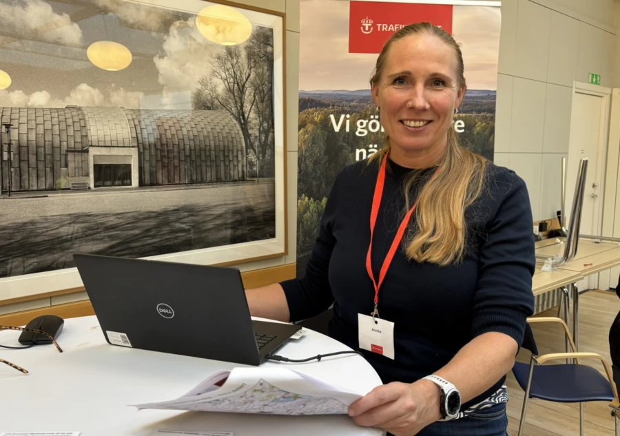 Leende kvinna med ljus h&aring;r i h&auml;stsvans vid en dator