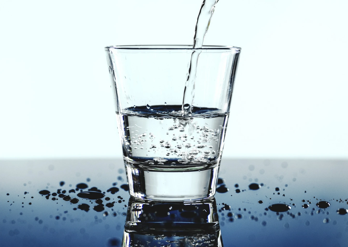 Halvfullt glas med vatten som fylls på.
