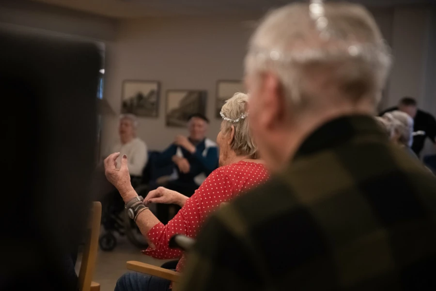 En &auml;ldre dam sitter p&aring; en stol och mimar att hon spelar fiol n&auml;r hon lyssna p&aring; musik.