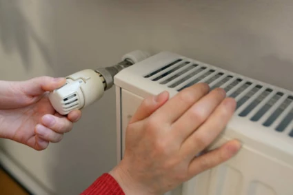 Person som vrider på en termostat på ett element