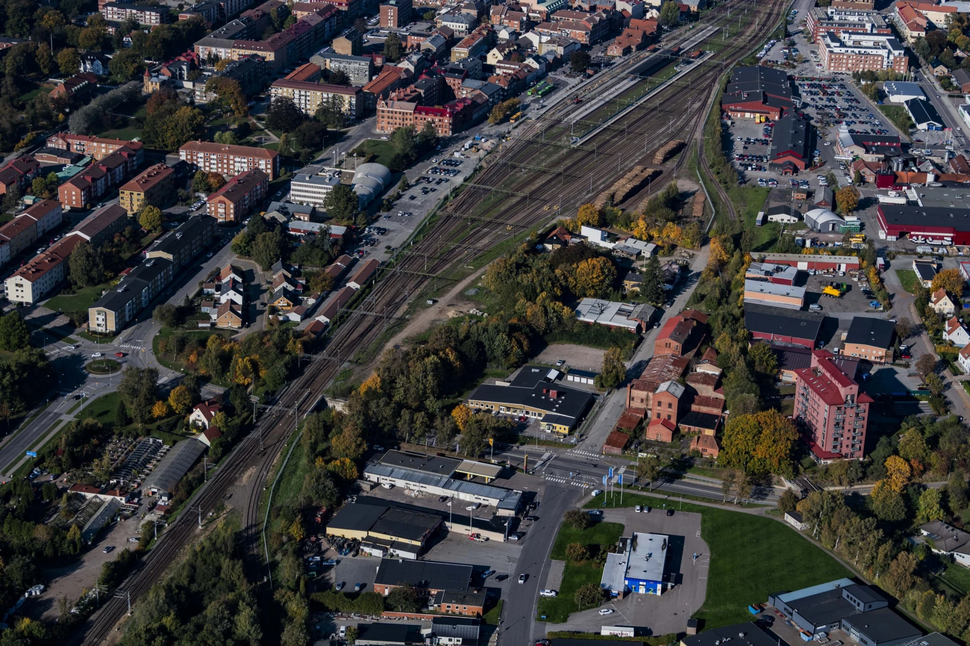 Flygbild över bangården med spår med stationen och alla spåren. Bebyggelse på båda sidor om spårområdet.