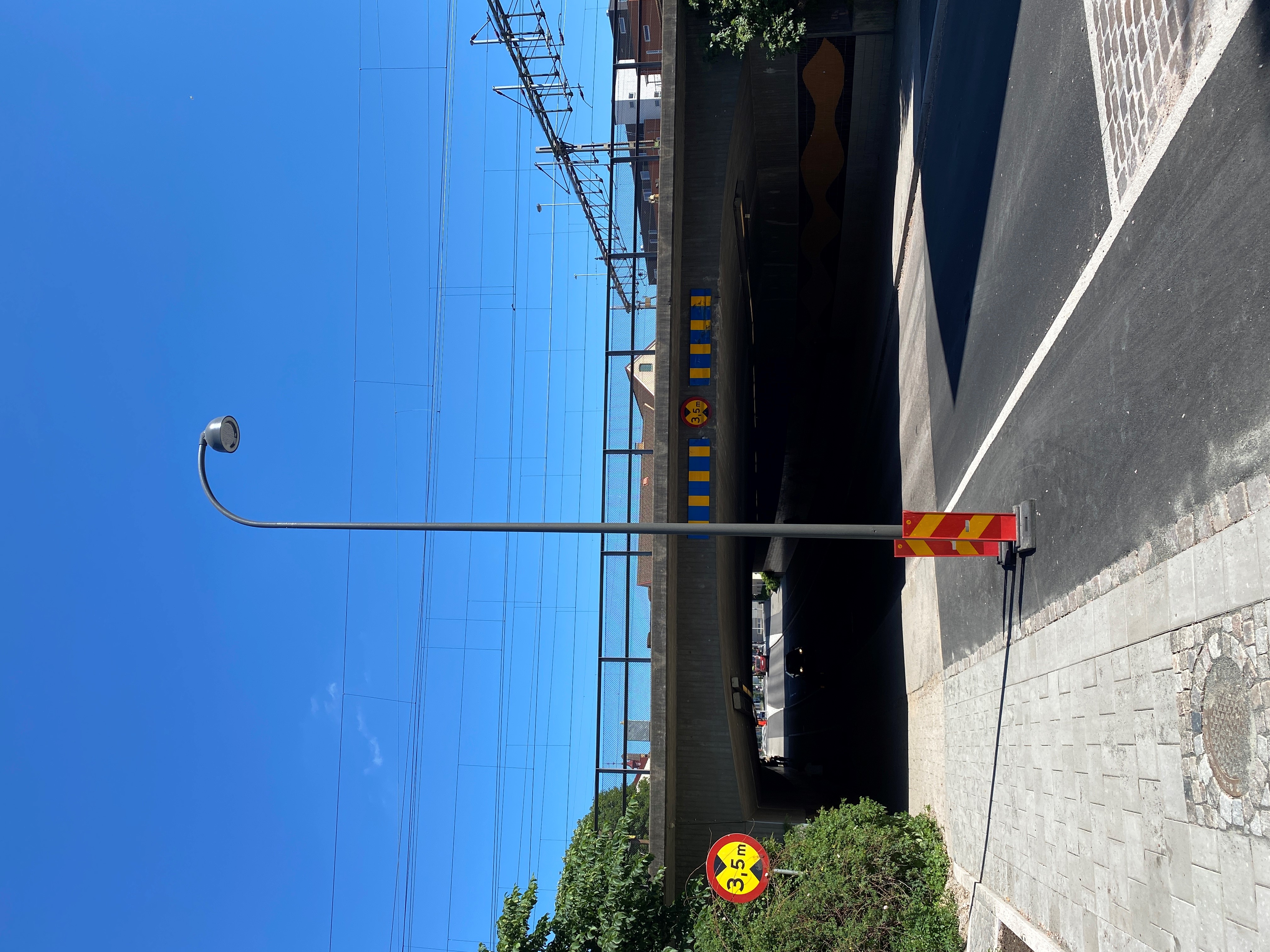 Lyktstople st&aring;r mitt i cykelbana. J&auml;rnv&auml;gsbro i bakgrunden.