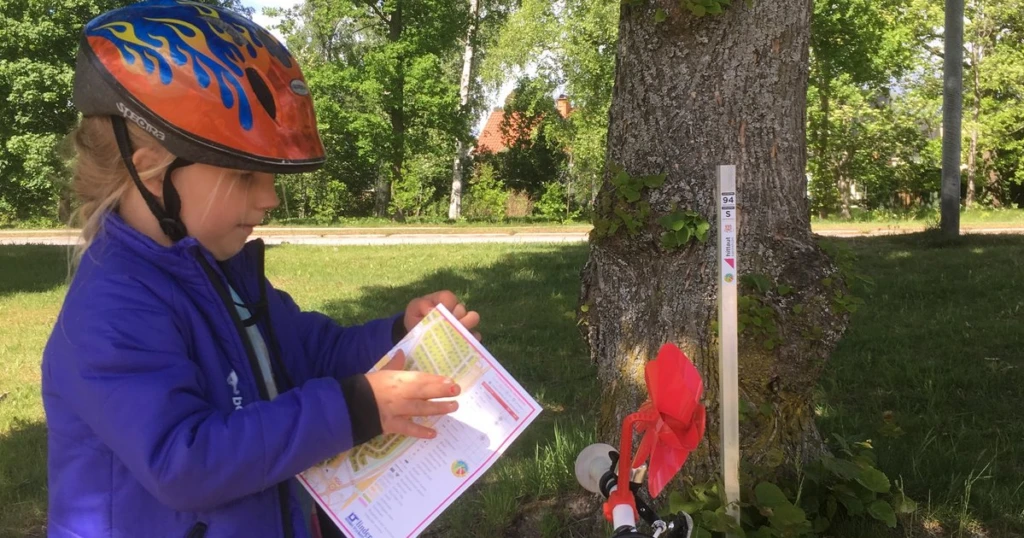Flicka med cykelhjälm som står med karta vid en av Hittauts check-points.