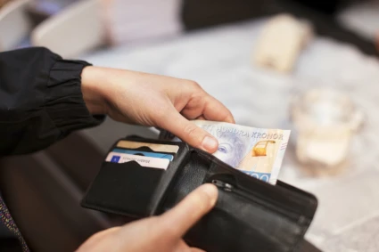 en person håller en plånbok med sedlar