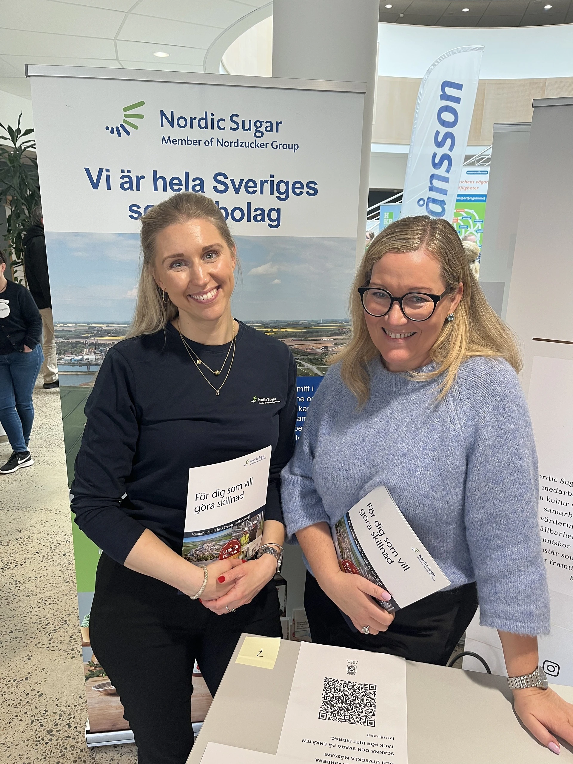Två medarbetare från nordic sugar står vid ett monter bord