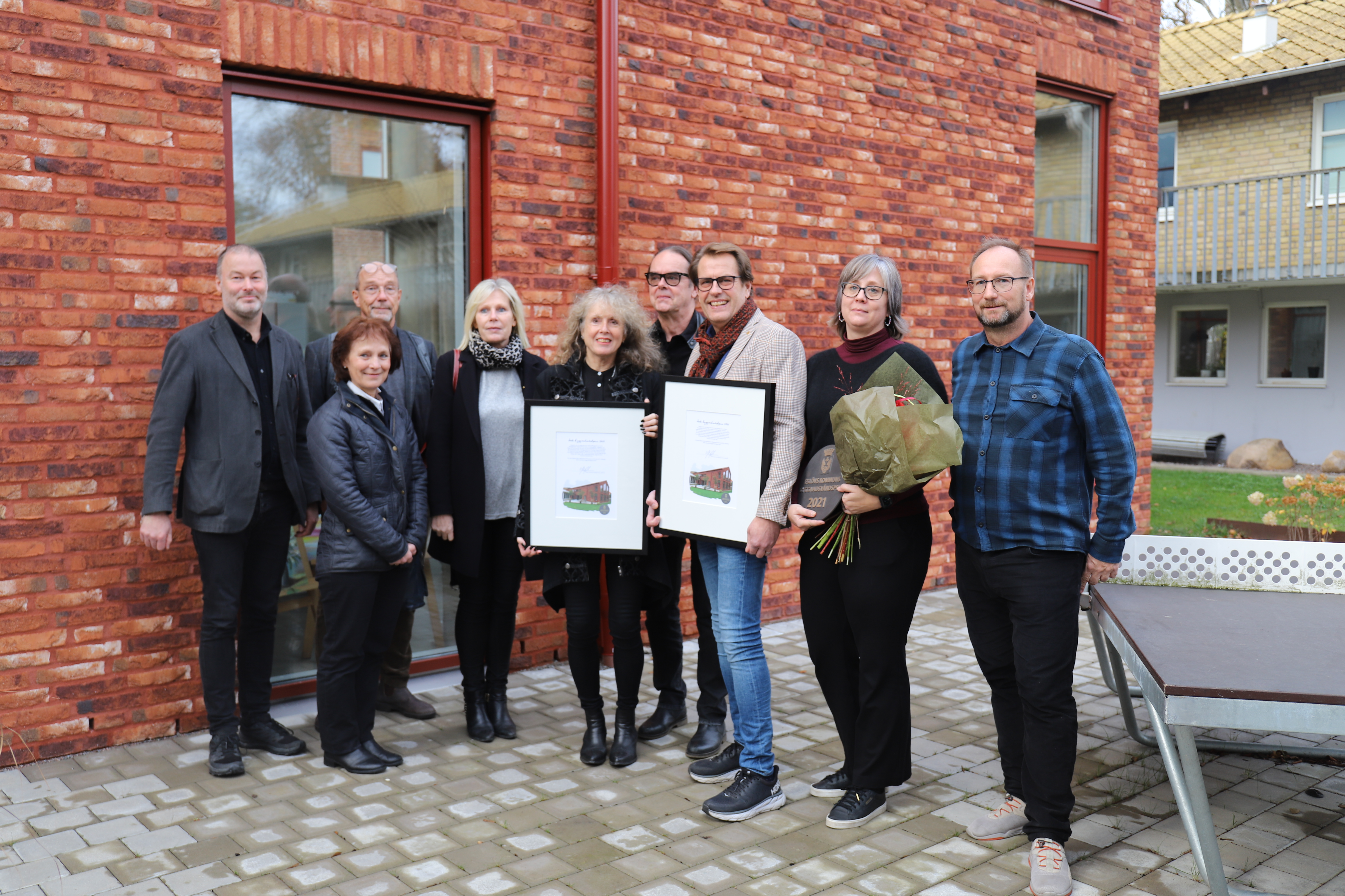 Esl&ouml;vs folkh&ouml;gskola tilldelas priset f&ouml;r tillbyggnaden av det s&aring; kallade Multihuset. Tillsammans med arkitektbyr&aring;n Lokal XXX Arkitekter har de arbetat fram utformningen av Multihuset. Fr&aring;n v&auml;nster: Mikael Vallberg, planchef, Catharina Malmborg (M), kommunstyrelsens f&ouml;rsta vice ordf&ouml;rande, Torsten Helender, planarkitekt, Eva Hallberg, kommundirekt&ouml;r, Berit Restad & Esbj&ouml;rn Jonsson, Lokal XXX Arkitekter, Ingemar Jeppsson, ordf&ouml;rande i Esl&ouml;vs Folkh&ouml;gskola, Ulrika Gleisner, rektor Esl&ouml;vs Folkh&ouml;gskola och Johan Andersson, kommunstyrelsens ordf&ouml;rande. 