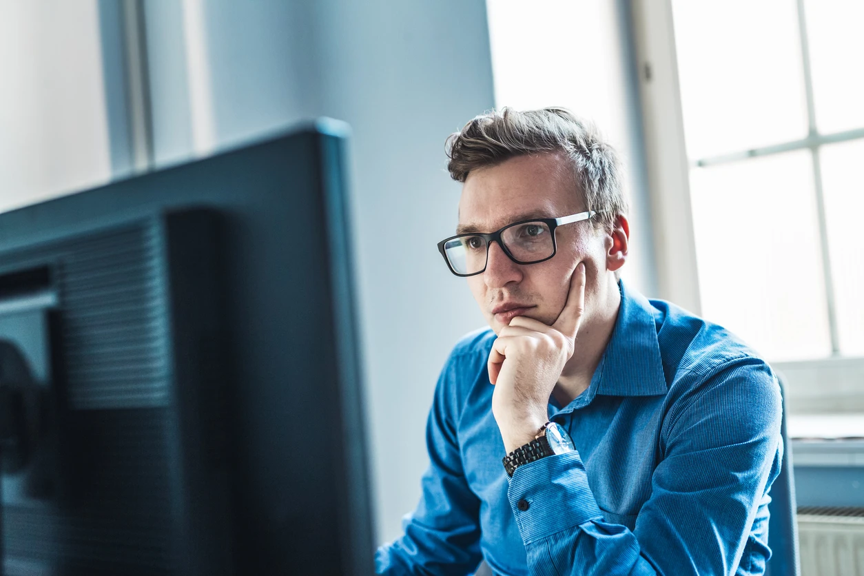Man i skjorta sitter framför en datorskärm