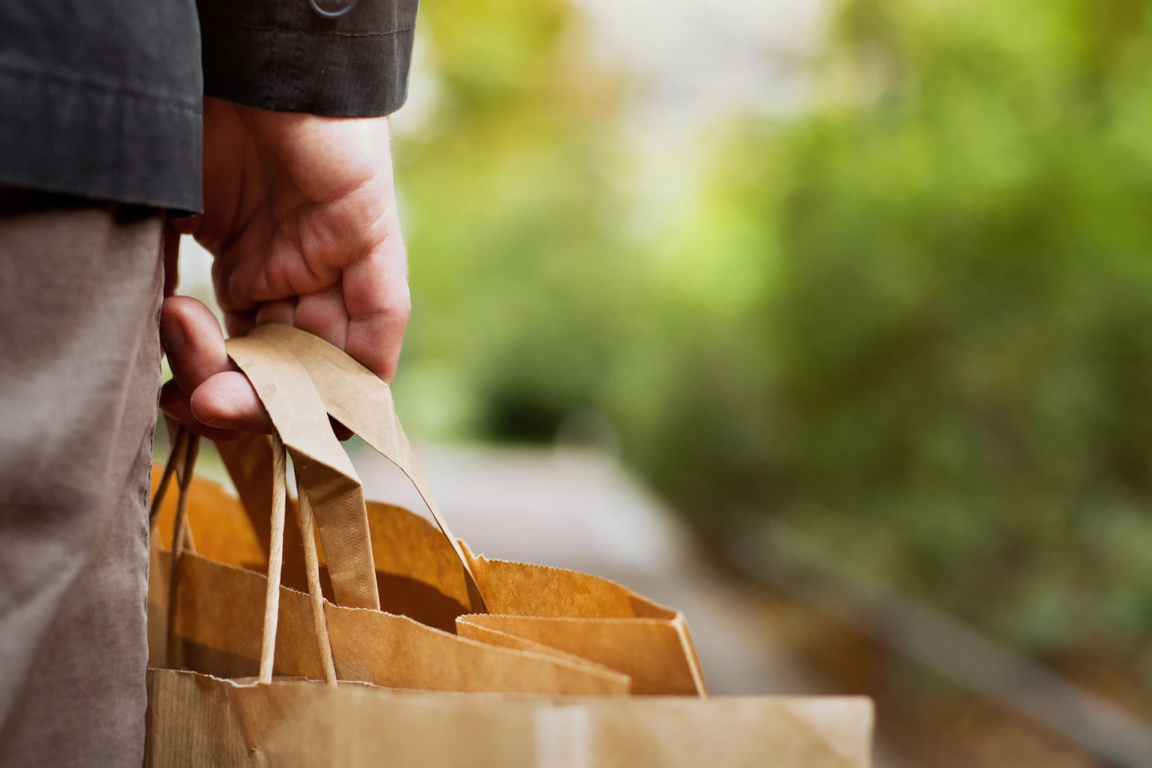 En hand som tillhör en äldre man håller i handtagen till en papperspåse