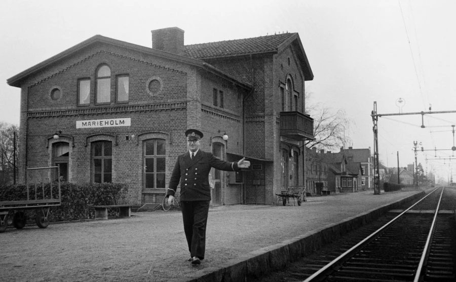 &Auml;ldre bild fr&aring;n 1920 p&aring; j&auml;rnv&auml;gsstationen i marieholm, en stins st&aring;r framf&ouml;r stationsbyggnaden och pekar