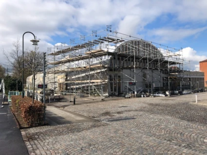 Medborgarhuset med ställningar, sett från entrésidan. Stenbeläggning i förgrunden.
