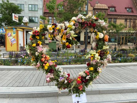 Hjärta av olika blommor med glasskiosken och hus på Södergatan i bakgrunden