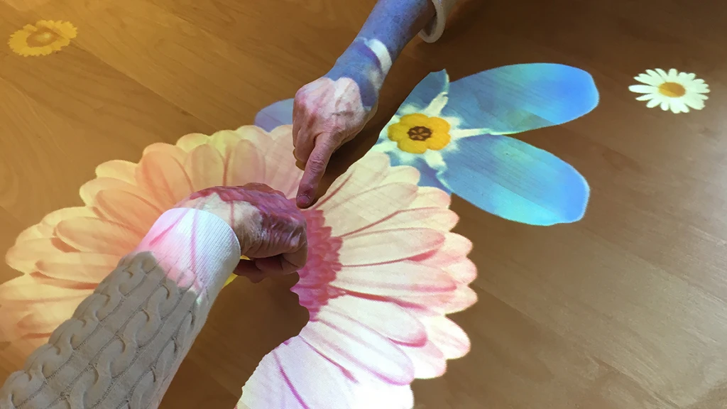 Händer som rör sig över en Tovertafel med blommor.