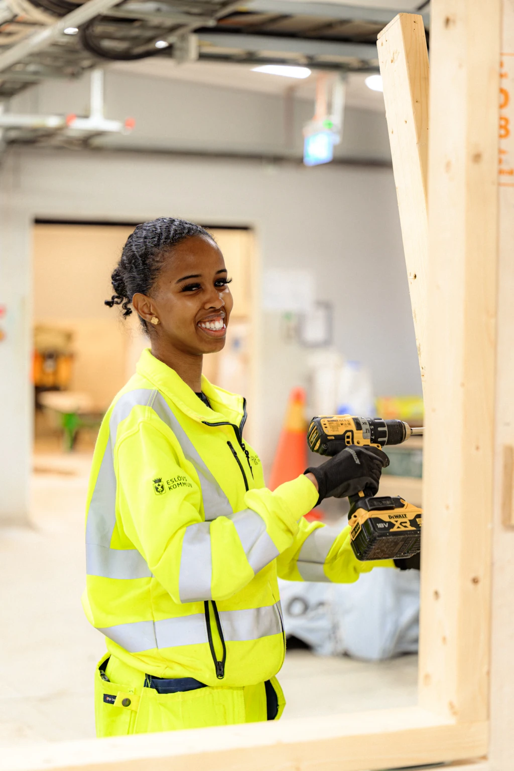 Tjej ler mot kameran med en borrmaskin