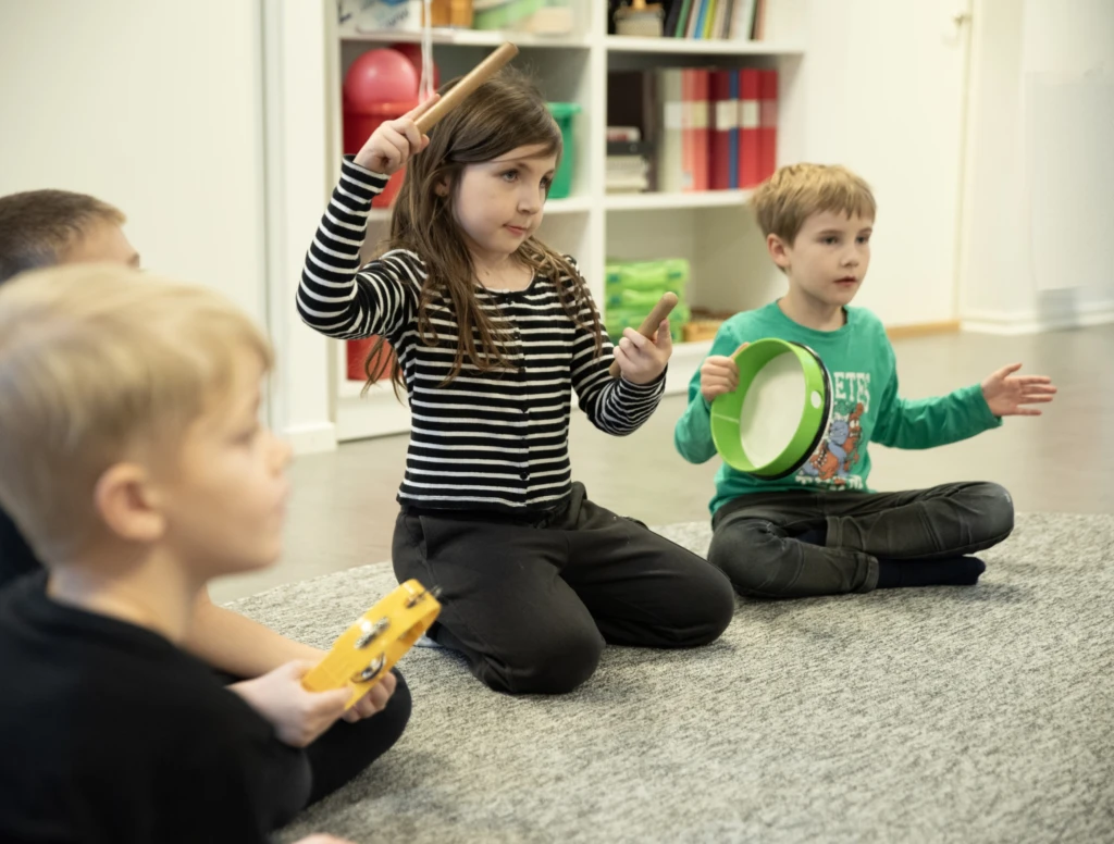 Pojkar och flicka spelar olika rytmikinstrument.