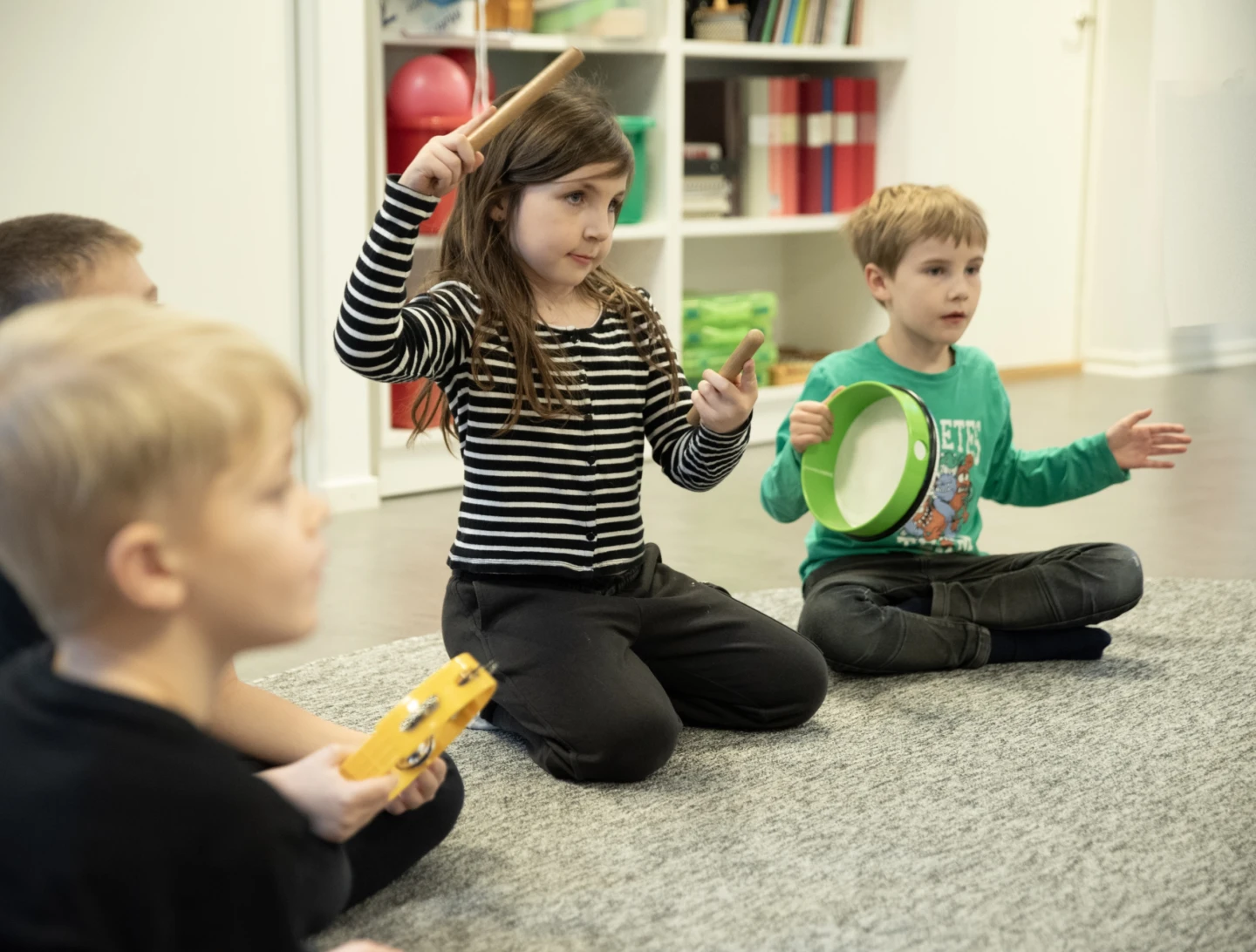 Pojkar och flicka spelar olika rytmikinstrument.