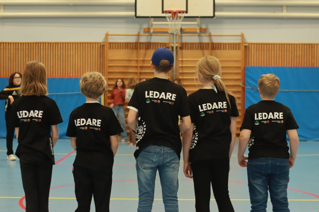 Fem unga i svarta t-shirts där det står Ledare i vitt på ryggen