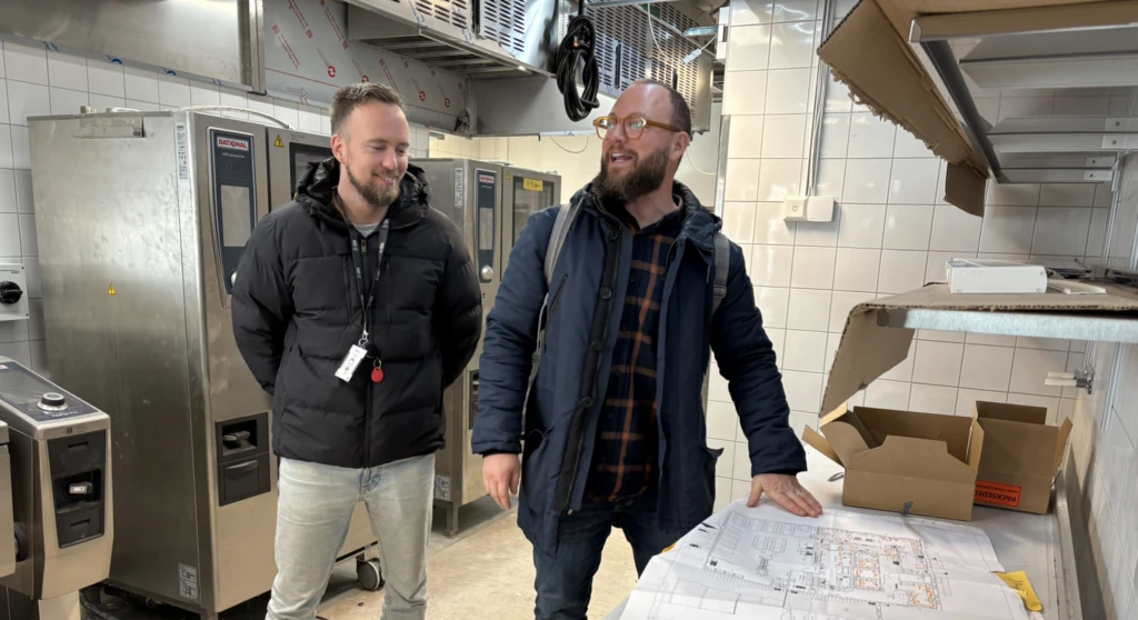 Två män tittar på ritningar i ett kök som håller på att byggas om