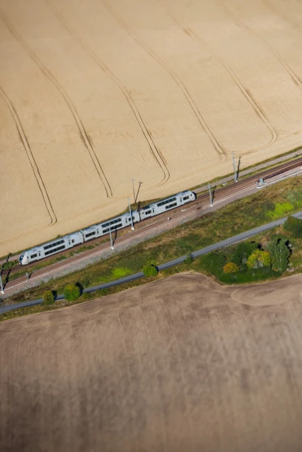Tåg körandes på räls i Skåne. åkrar vid sidan om