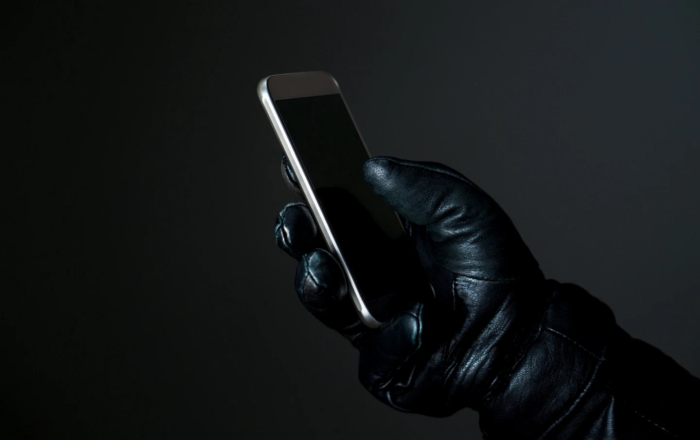 En handskllädd hand med en telefon.