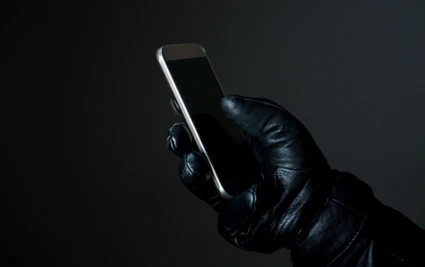 En handskllädd hand med en telefon.