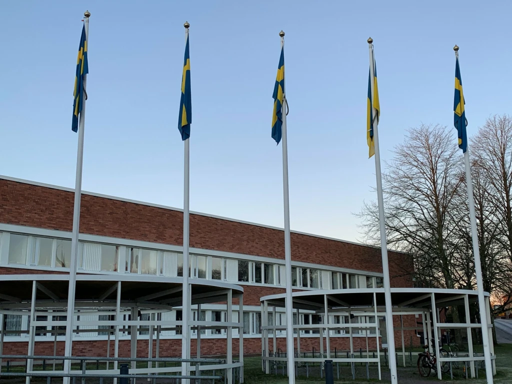Fyra flaggor framför stadshuset. Vädret är fint och det blåser inte, så flaggorna hänger ner.