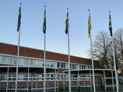 Fyra flaggor framför stadshuset. Vädret är fint och det blåser inte, så flaggorna hänger ner.