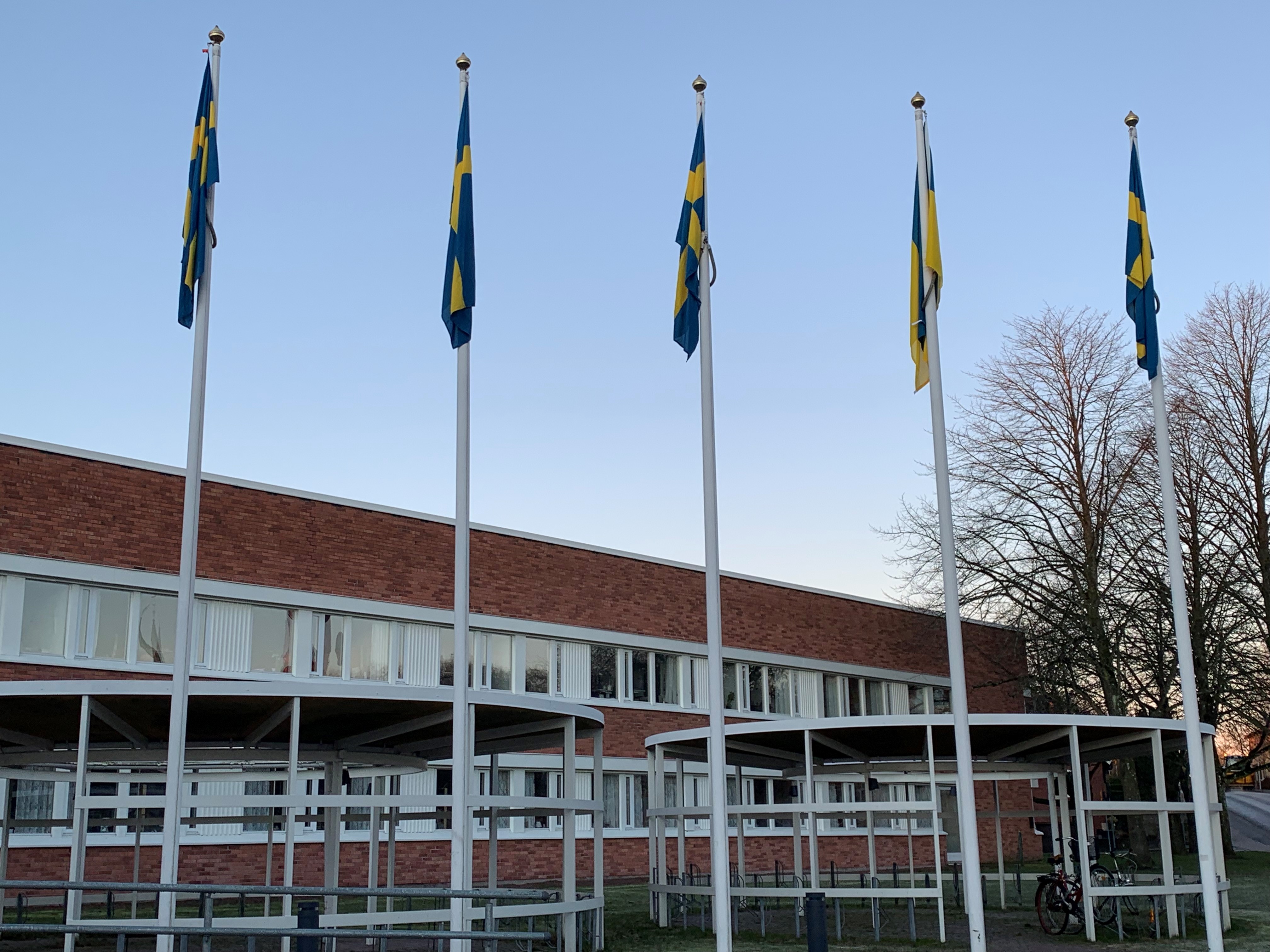 Fyra flaggor framf&ouml;r stadshuset. V&auml;dret &auml;r fint och det bl&aring;ser inte, s&aring; flaggorna h&auml;nger ner.
