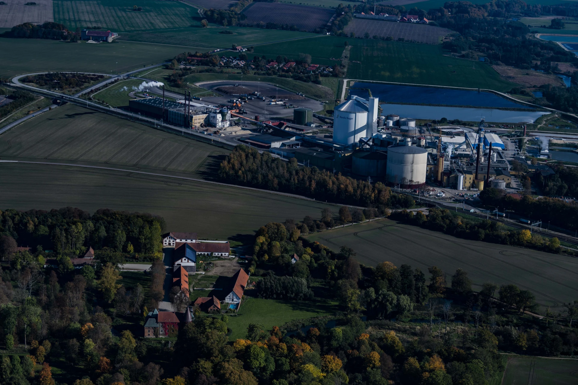 Flygbild över hus, åkrar och en fabrik