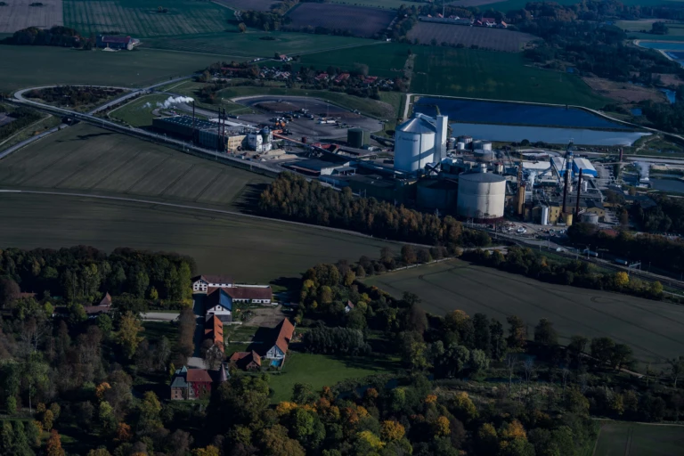 Flygbild över hus, åkrar och en fabrik